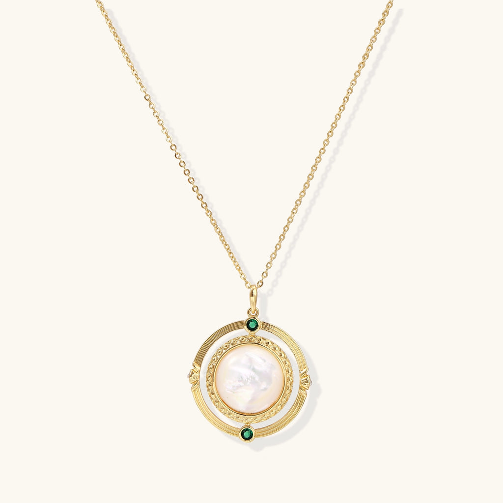 Gold-plated pendant necklace with circular orbital design, iridescent mother-of-pearl center and green zirconia accents