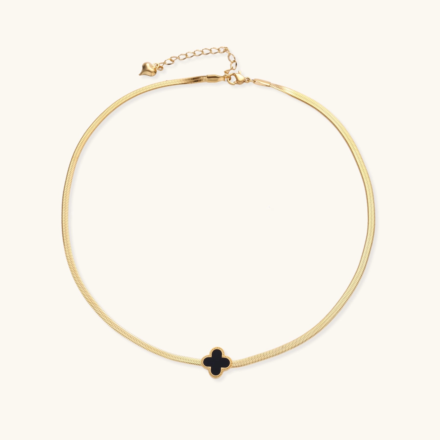 Delicate gold-plated chain necklace featuring a black quatrefoil clover pendant on white background.
