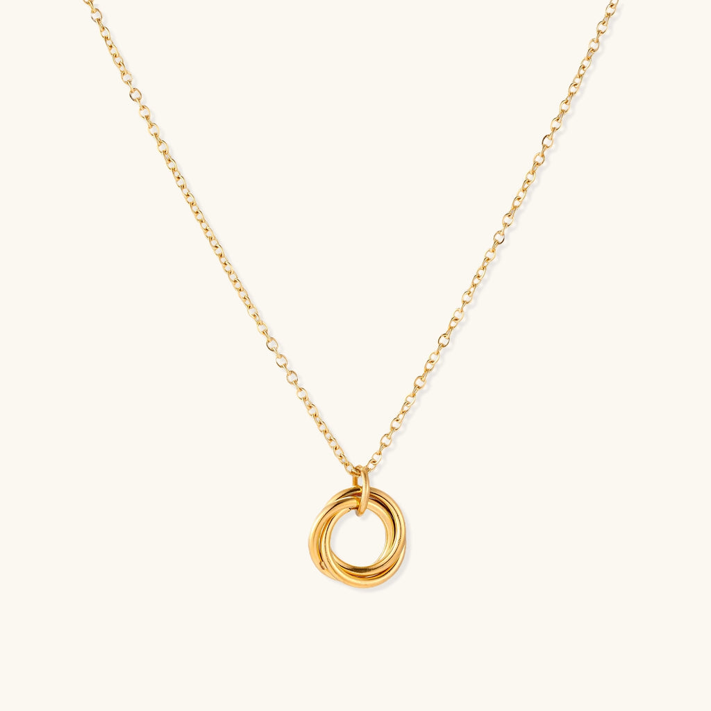 Close-up of a gold-plated stainless steel necklace with interlocking twisted ring pendant on white background